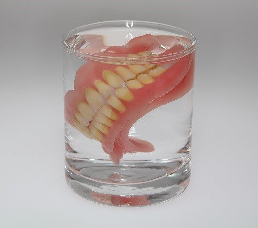 Die klassische Zahnprothese für Ober- und Unterkiefer im Wasserglas